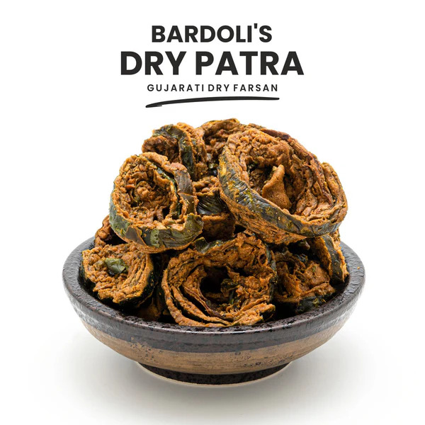 Slices of Gujarati patra showing a spiral of green leaf and yellow gram-flour batter, topped with sesame seeds.